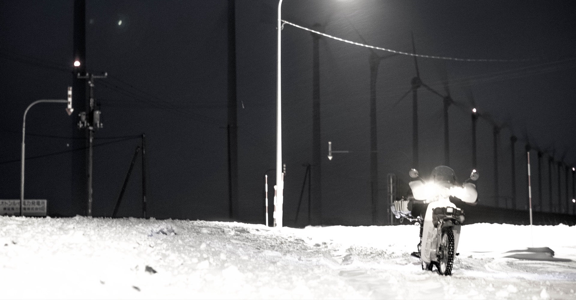 夜の風車群と雪道のバイク